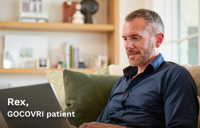 GOCOVRI patient Rex using his laptop while sitting on a comfortable chair. 
